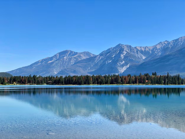 A stunning view of snow-capped mountains reflecting in a clear lake